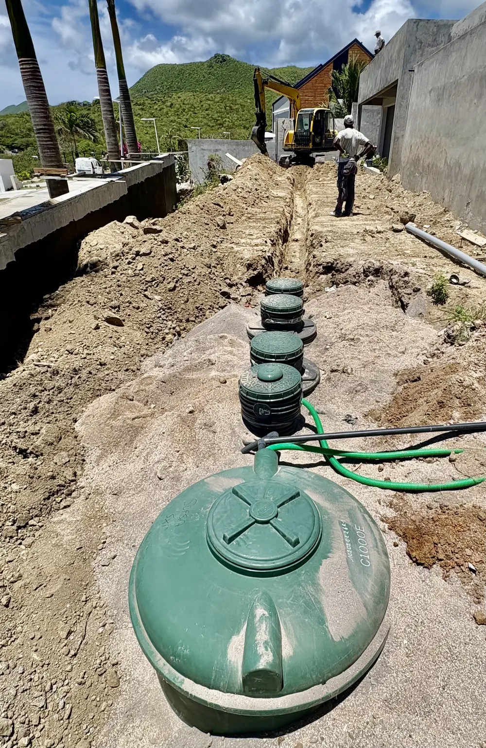 Tranchée et alignement de cuves d'assainissement autonome en cours d'installation le long d'une villa à Saint-Martin